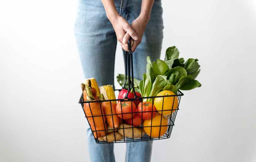 woman carrying basket of fruits and vegetables
